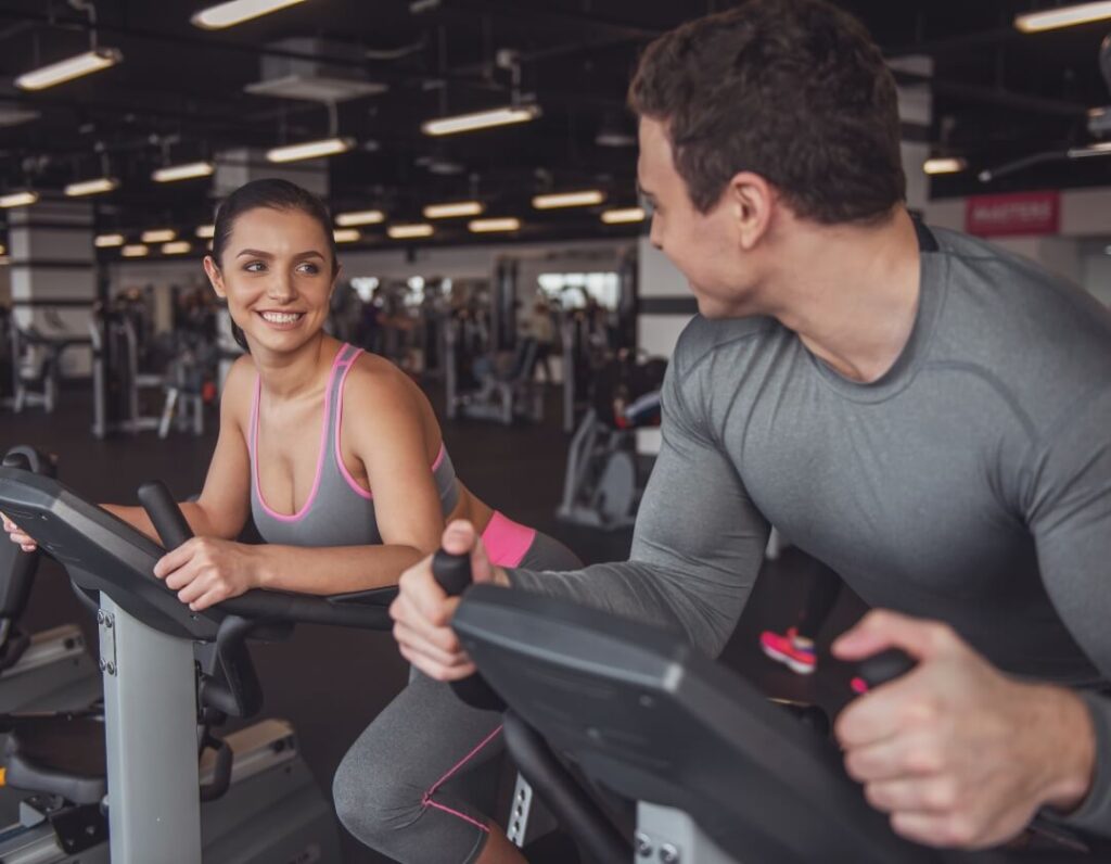 Fit couple in the gym performing cardio exercises.