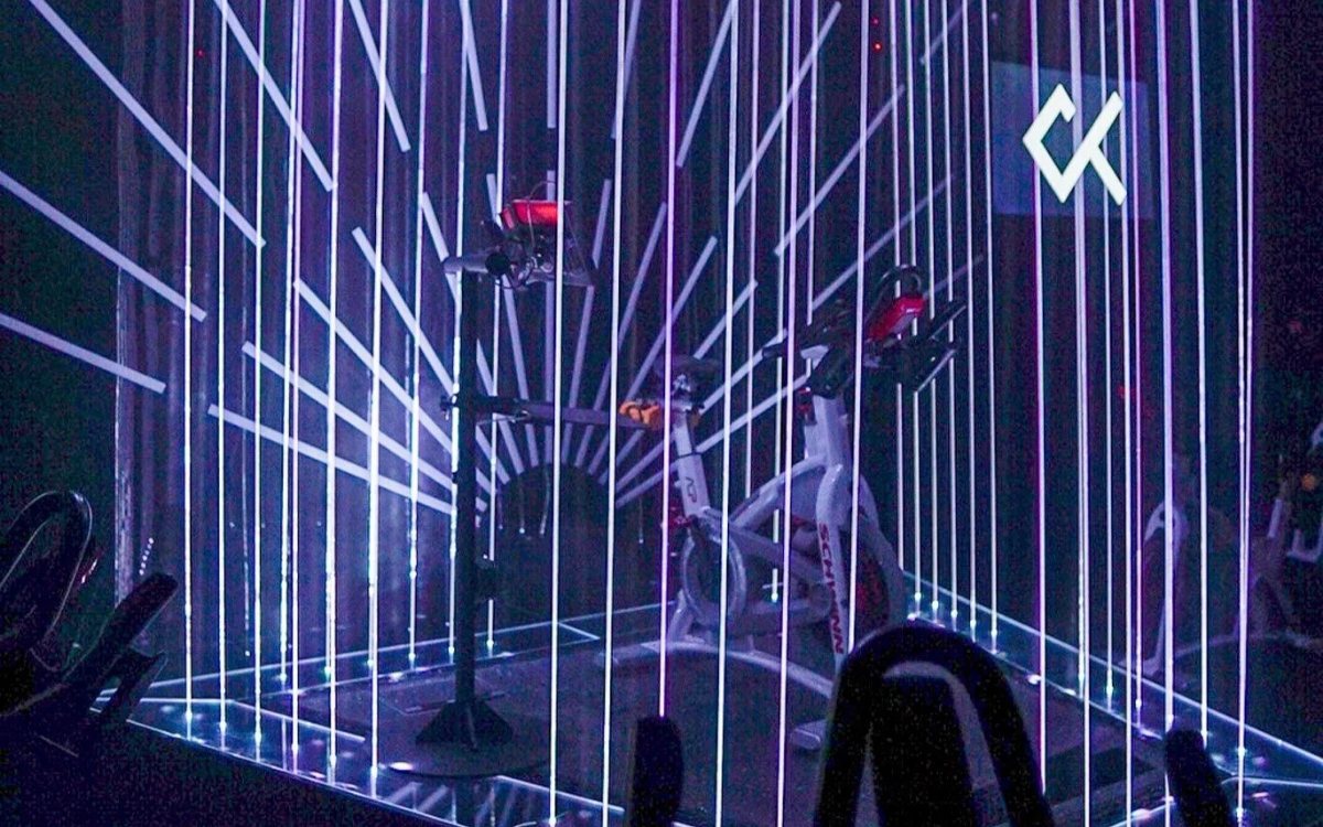 The RIDE room at CRANK, spin bikes under a neon light rig