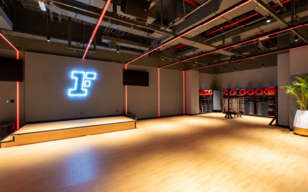 A group exercise studio at Fitness First, with a wooden floor and weight racks along the wall