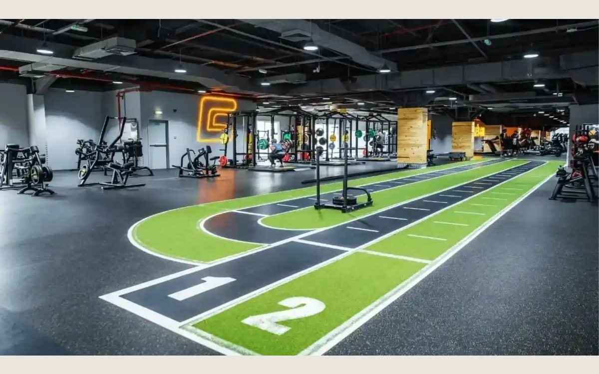 The gym floor at GymNation Al Quoz, with squat racks, a sled track and plate loaded machines
